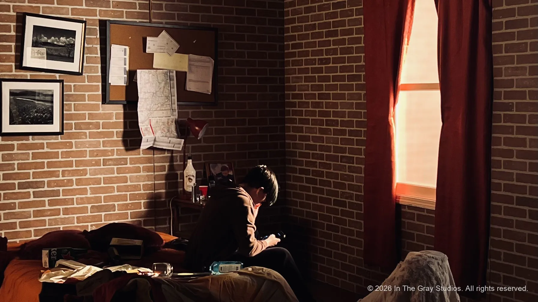 A brick-walled room in low warm light, a figure resting near the window